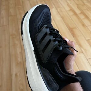 It is Adidas ultra boost light shoes with black colour and white sole.